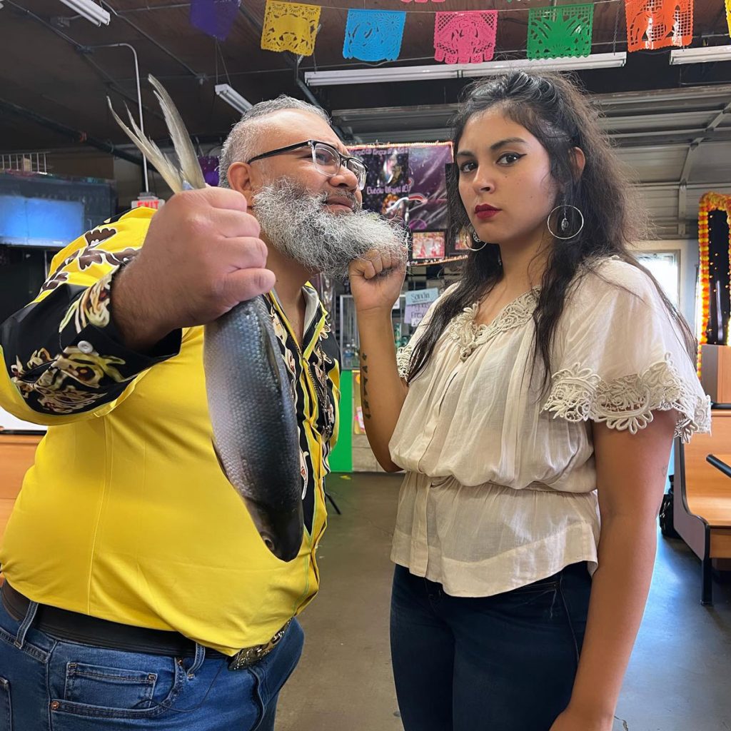 Eunice grabbing Marcos by the beard while he is holding a fish